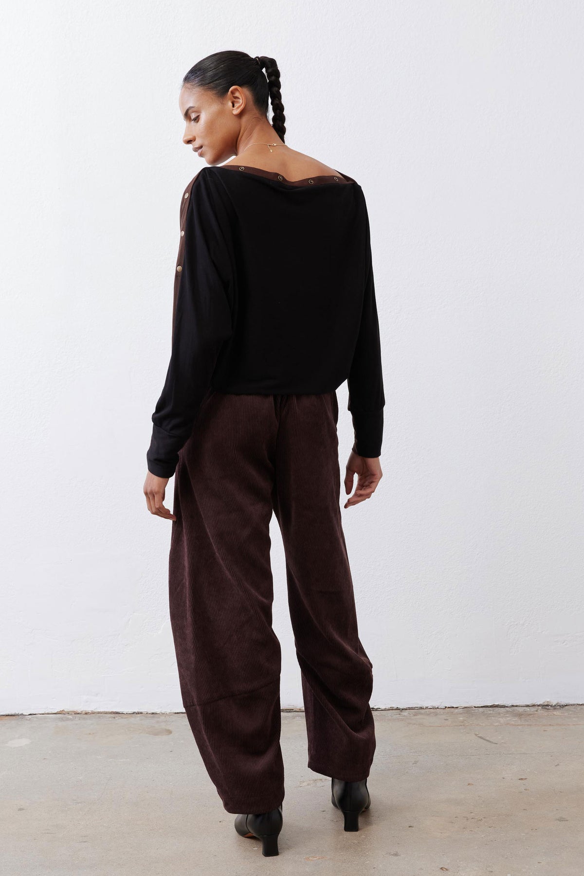 Black long-sleeve top with round back neckline and snap-button details