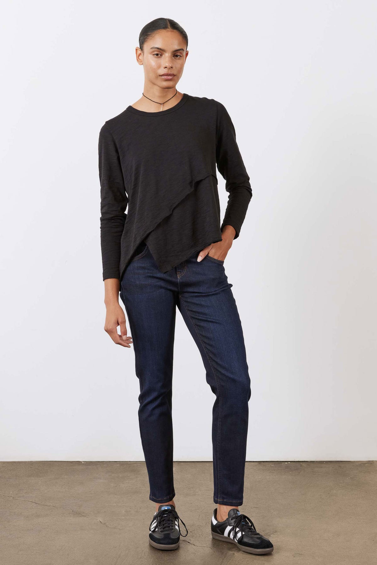 Black asymmetric long sleeve top with curved draped hem and crew neckline