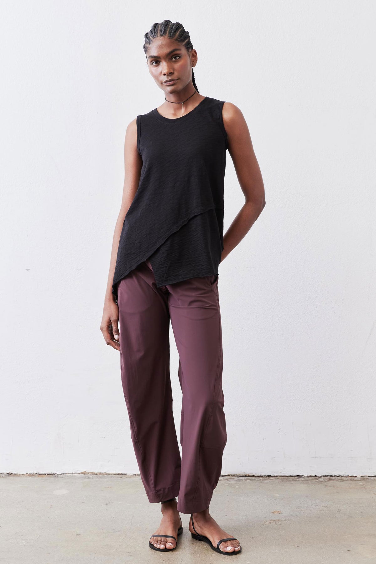 Black asymmetric tank top with draped front hem, sleeveless look.