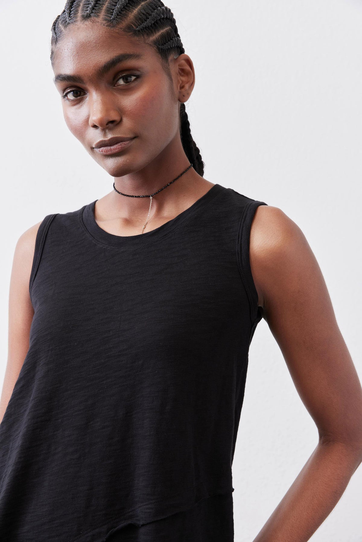 Black sleeveless asymmetric tank top, crew neck and draped hem.