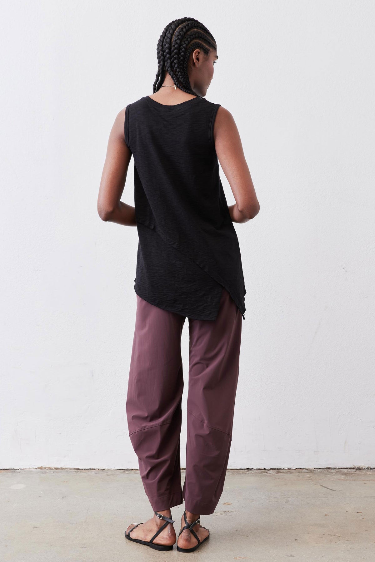 Black asymmetric tank top with draped hem, sleeveless back view.