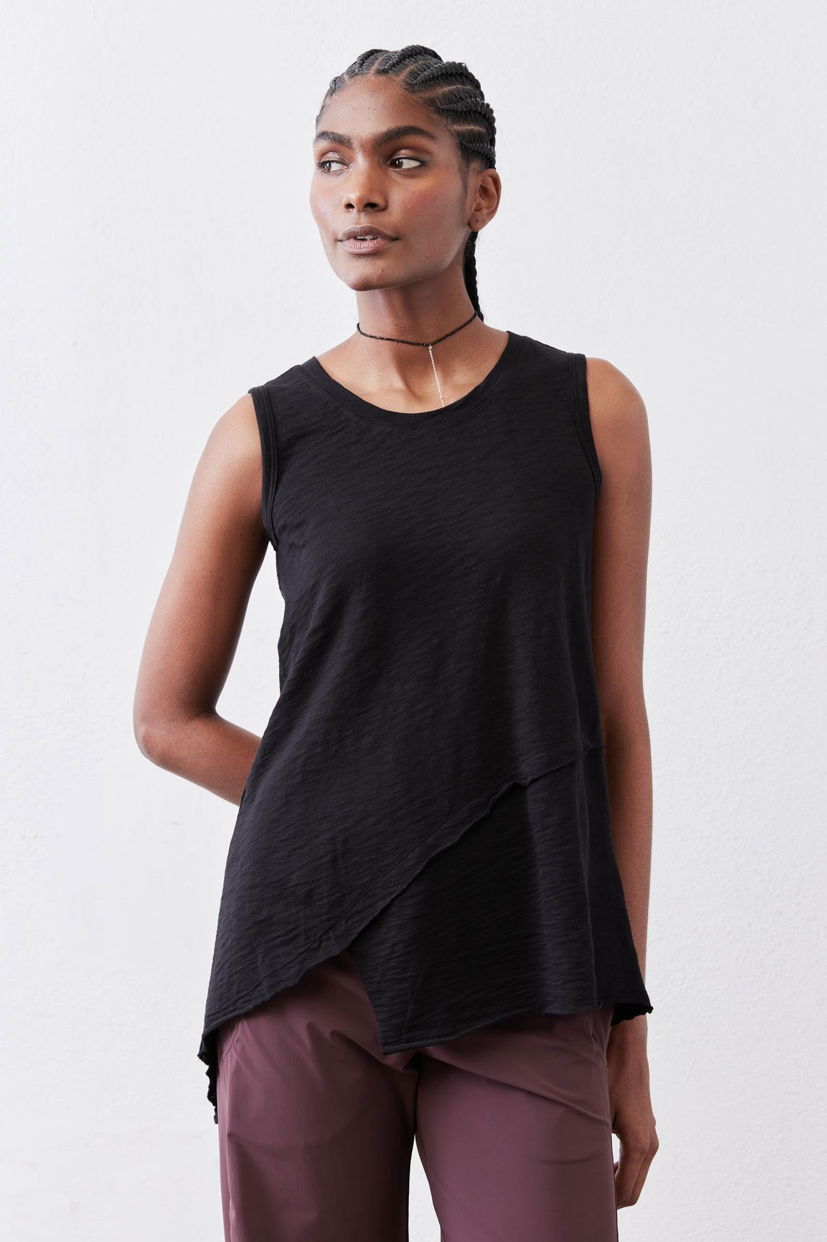 Black asymmetric sleeveless tank with angled drape hem detail.