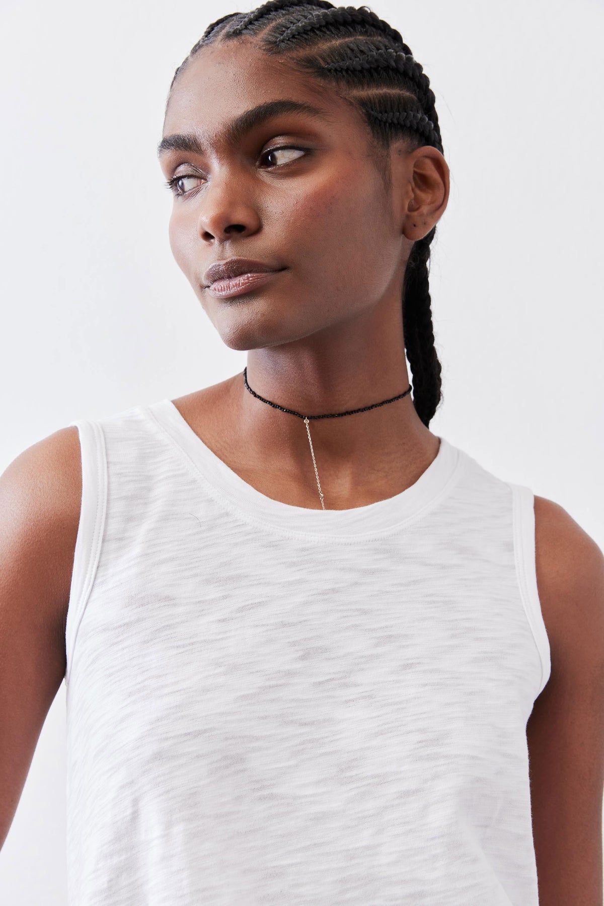 White crew-neck sleeveless tank top close-up with thin choker necklace detail