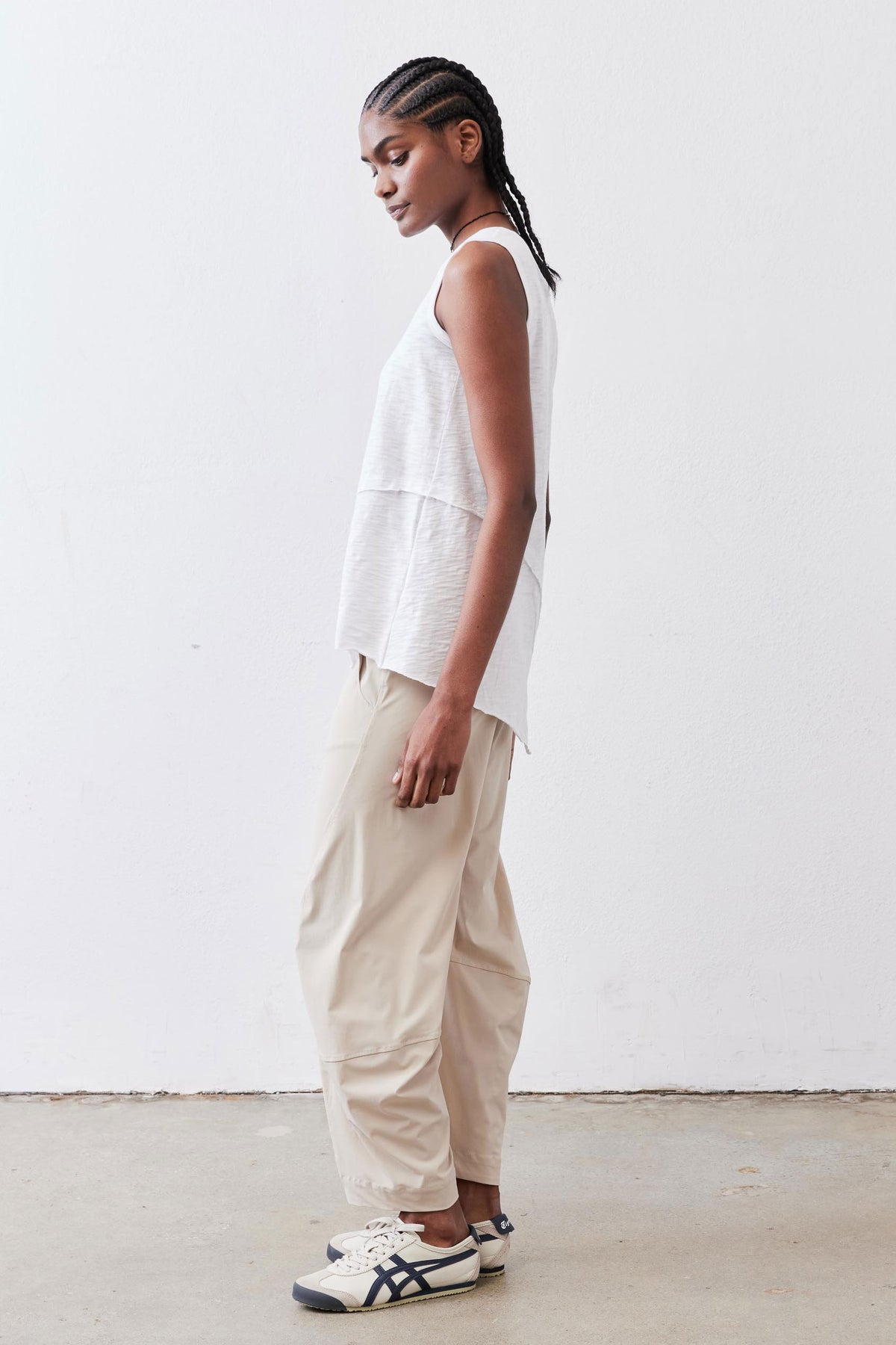 White sleeveless asymmetric tank top in side profile, crew neck and high-low hem