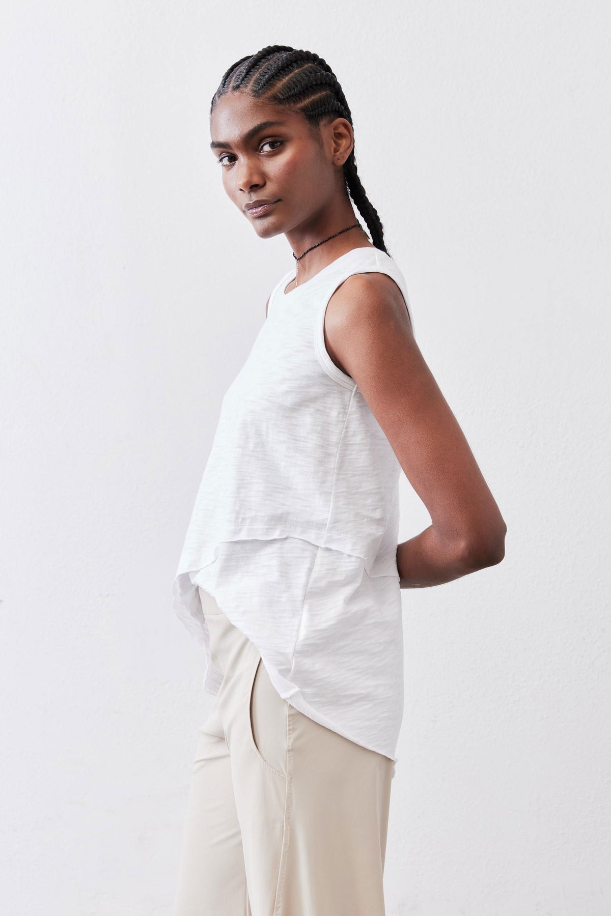 White asymmetric tank top from a three-quarter back angle, layered hem
