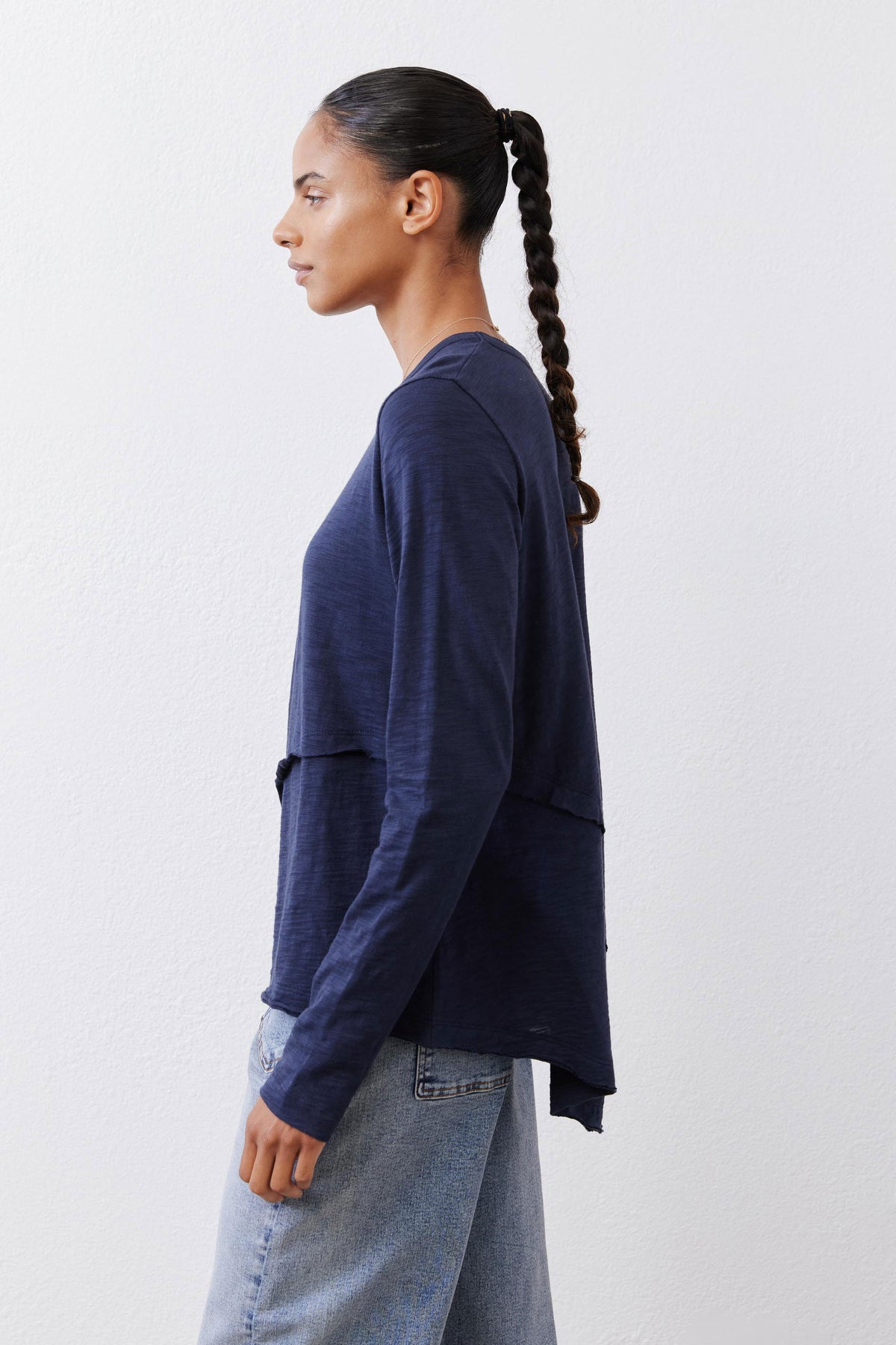 Navy asymmetric long sleeve top, crew neck, draped side hem, profile view