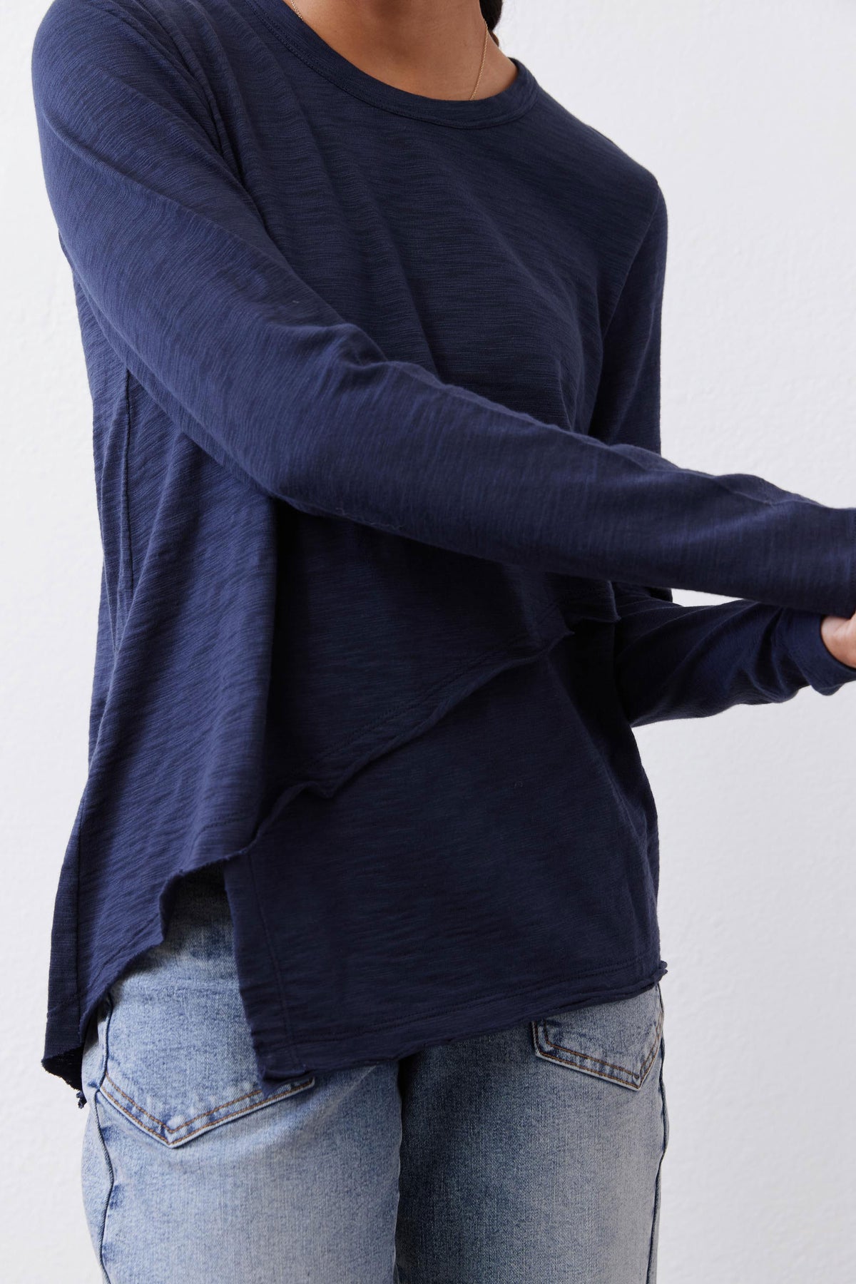 Navy long sleeve knit top with crew neck and draped diagonal hem