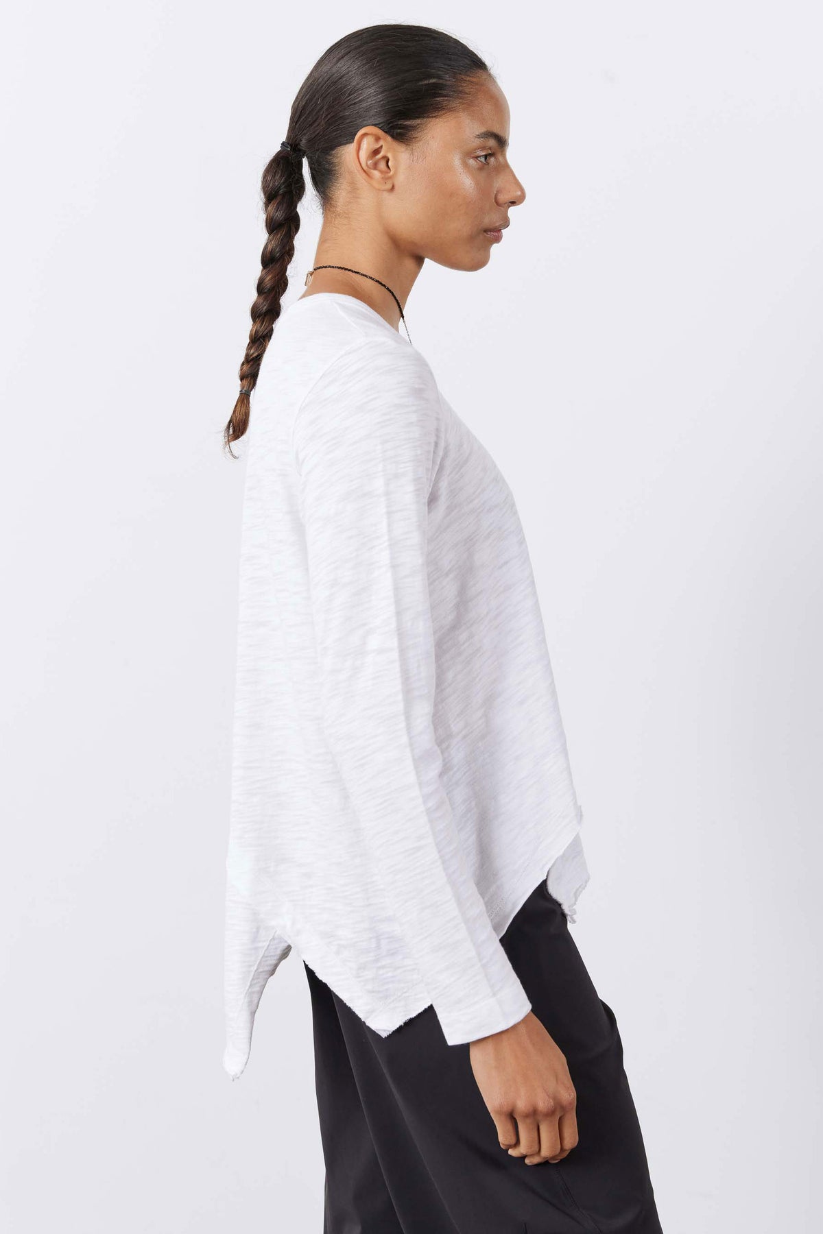 White long sleeve asymmetric top, side view with flowing uneven hem