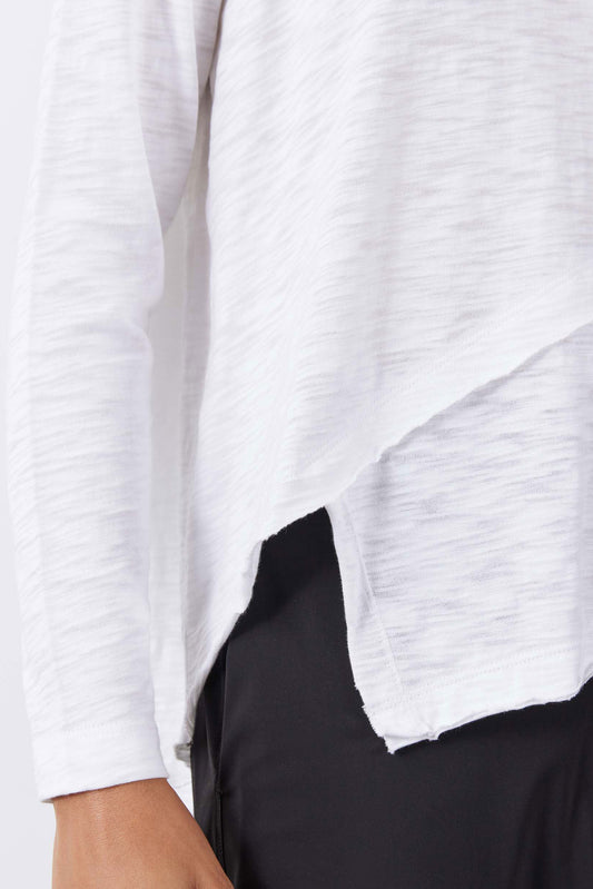 White asymmetric long sleeve top close-up, slanted hem and curved side detail