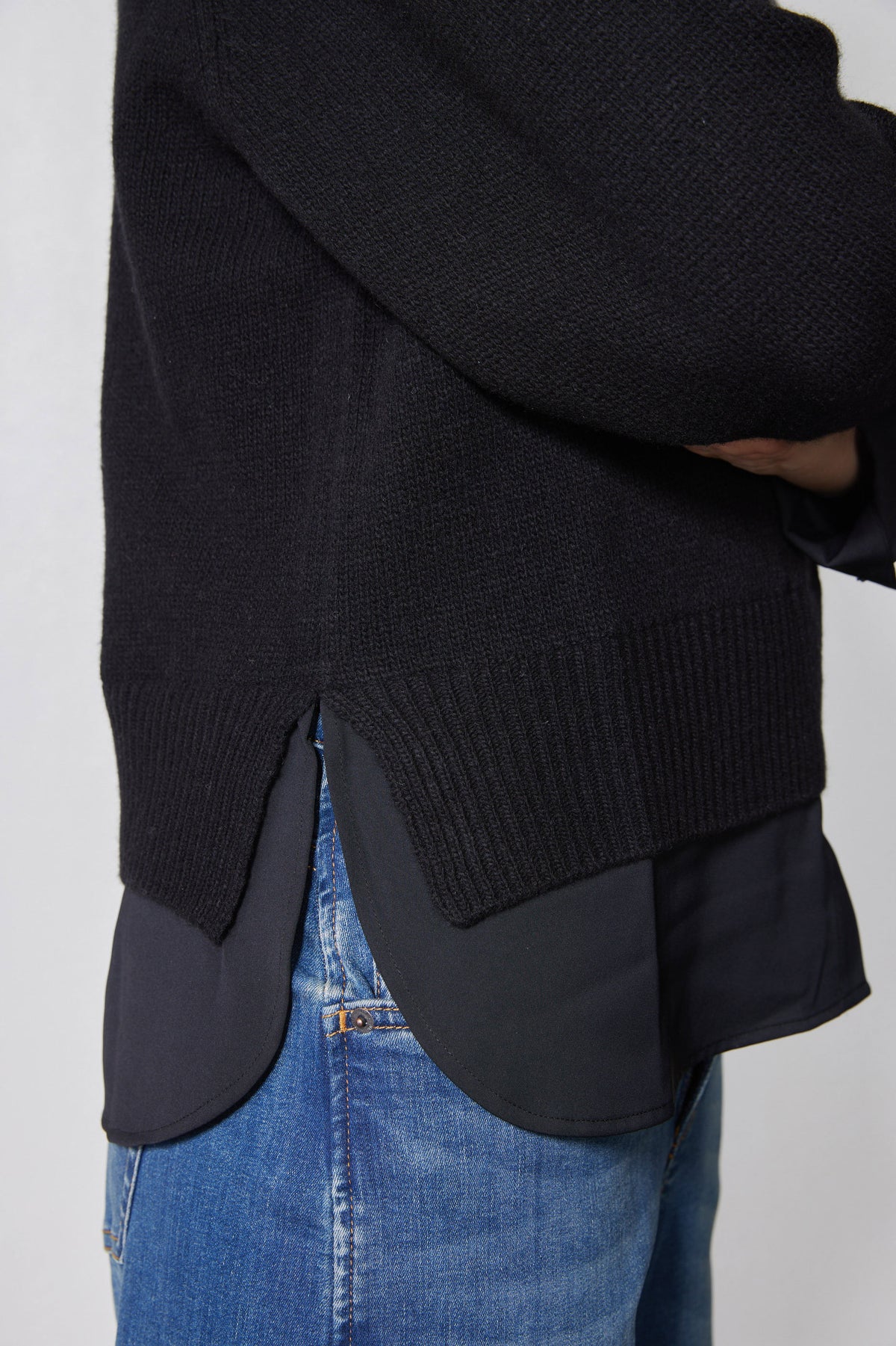 Black knit pullover sweater shirt hem with dark underlayer peeking out