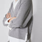 Side view of gray pullover sweater with white shirt underneath and buttoned cuff detail