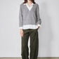 Gray knit pullover sweater with V-neck over white collared shirt and buttoned placket