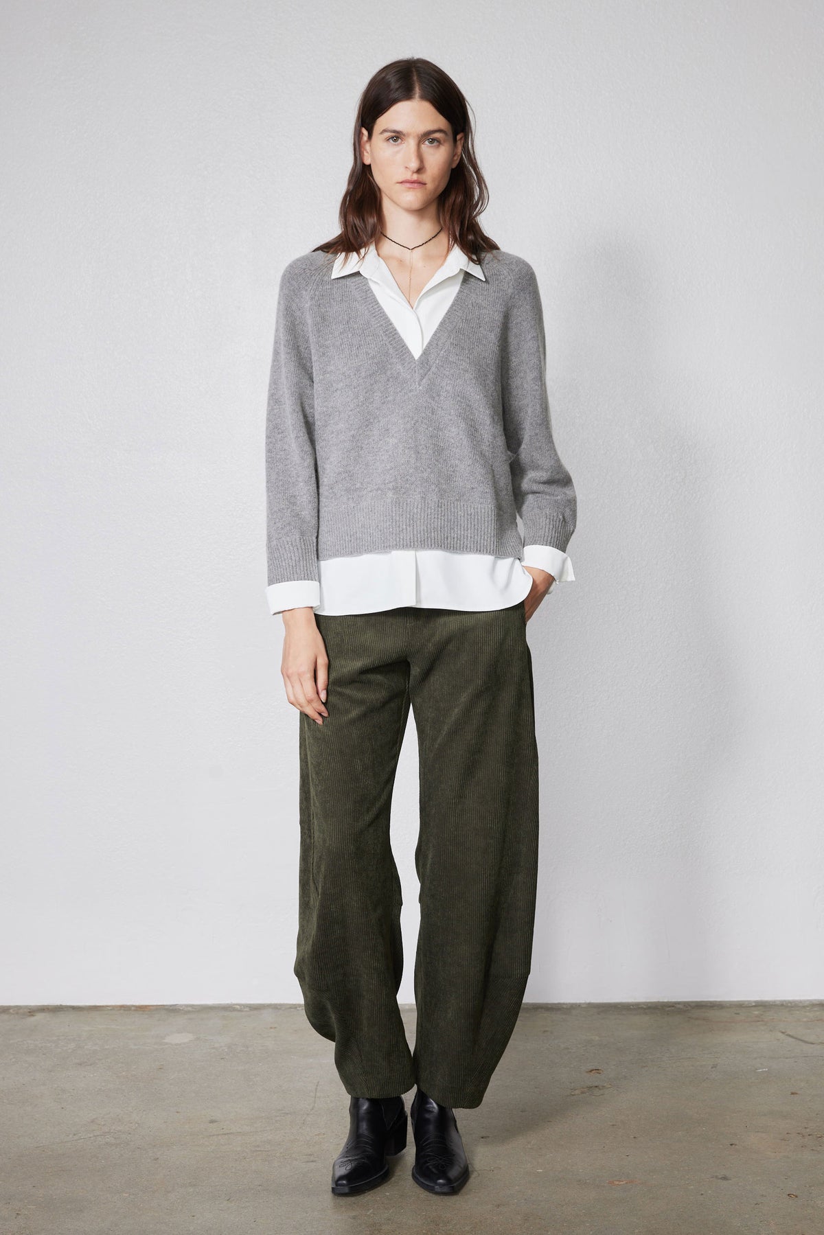 Gray knit pullover sweater with V-neck over white collared shirt and buttoned placket