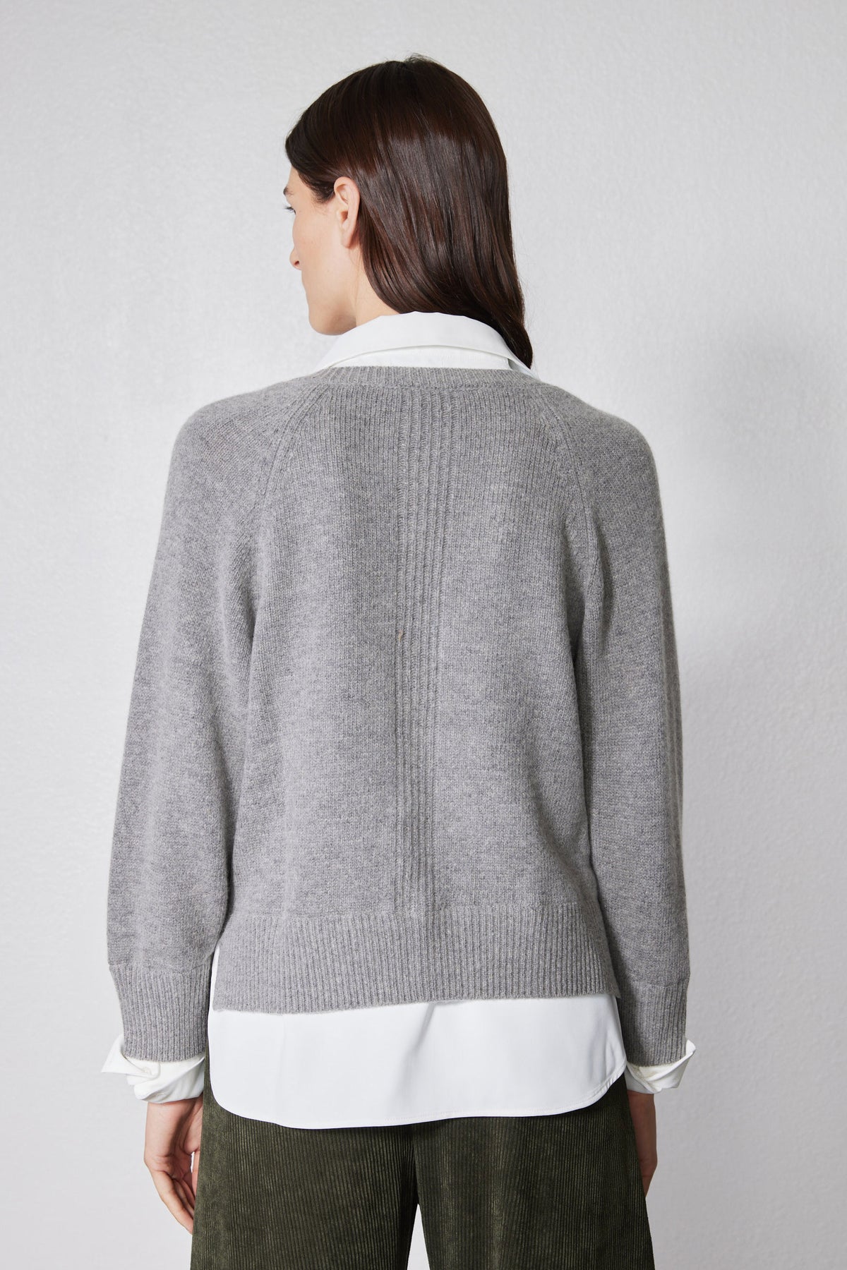 Back view of gray knit pullover sweater with ribbed hem and white shirt layer