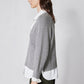 Gray knit pullover sweater in side profile with white shirt hem peeking below