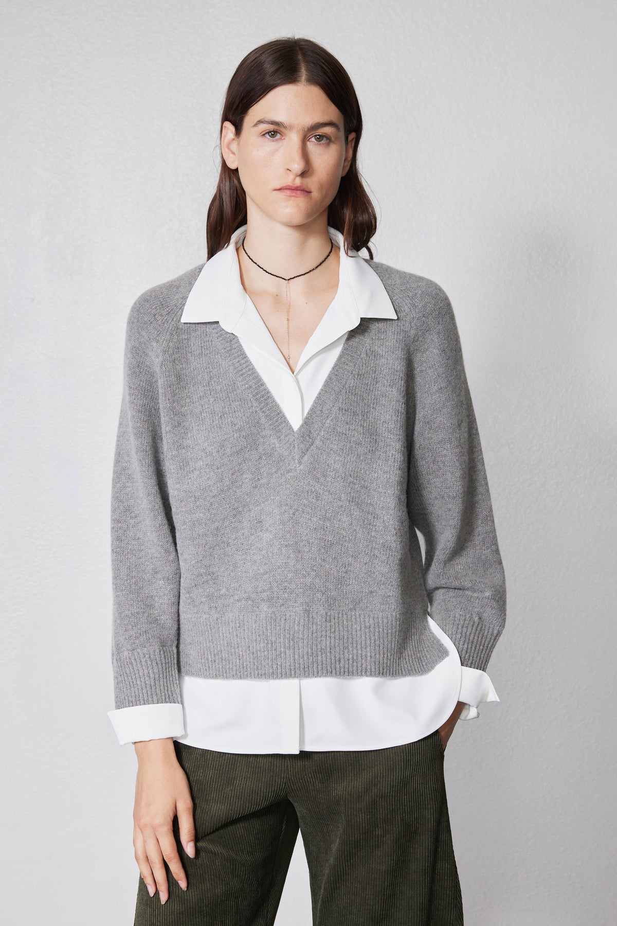 Gray V-neck pullover sweater with white collared shirt layer and ribbed cuffs