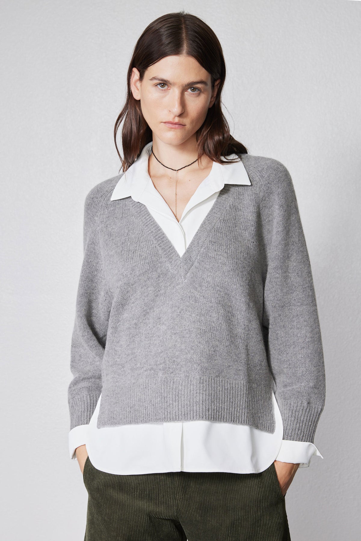 Front view of gray pullover sweater with white shirt placket detail at V-neck hem