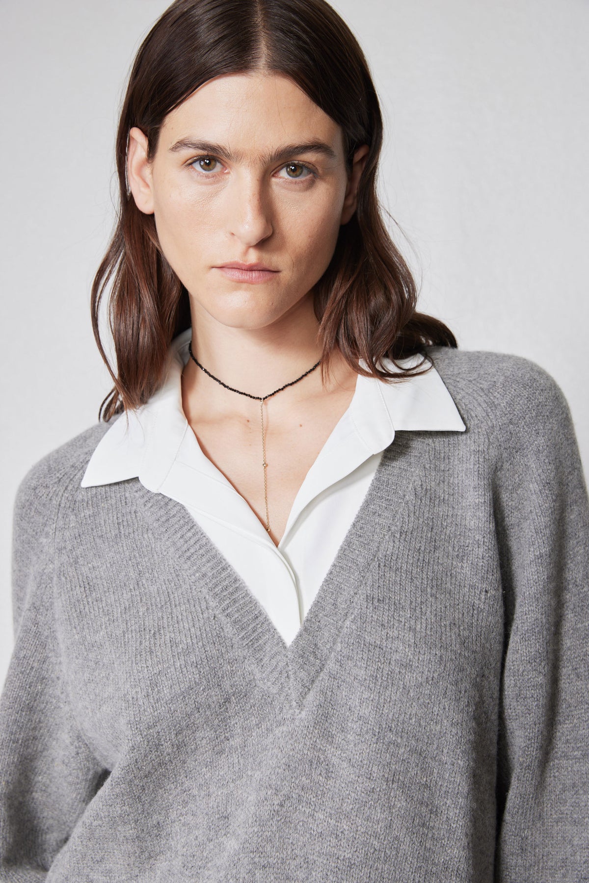 Close-up of gray sweater and white collared shirt at V-neck with layered neckline