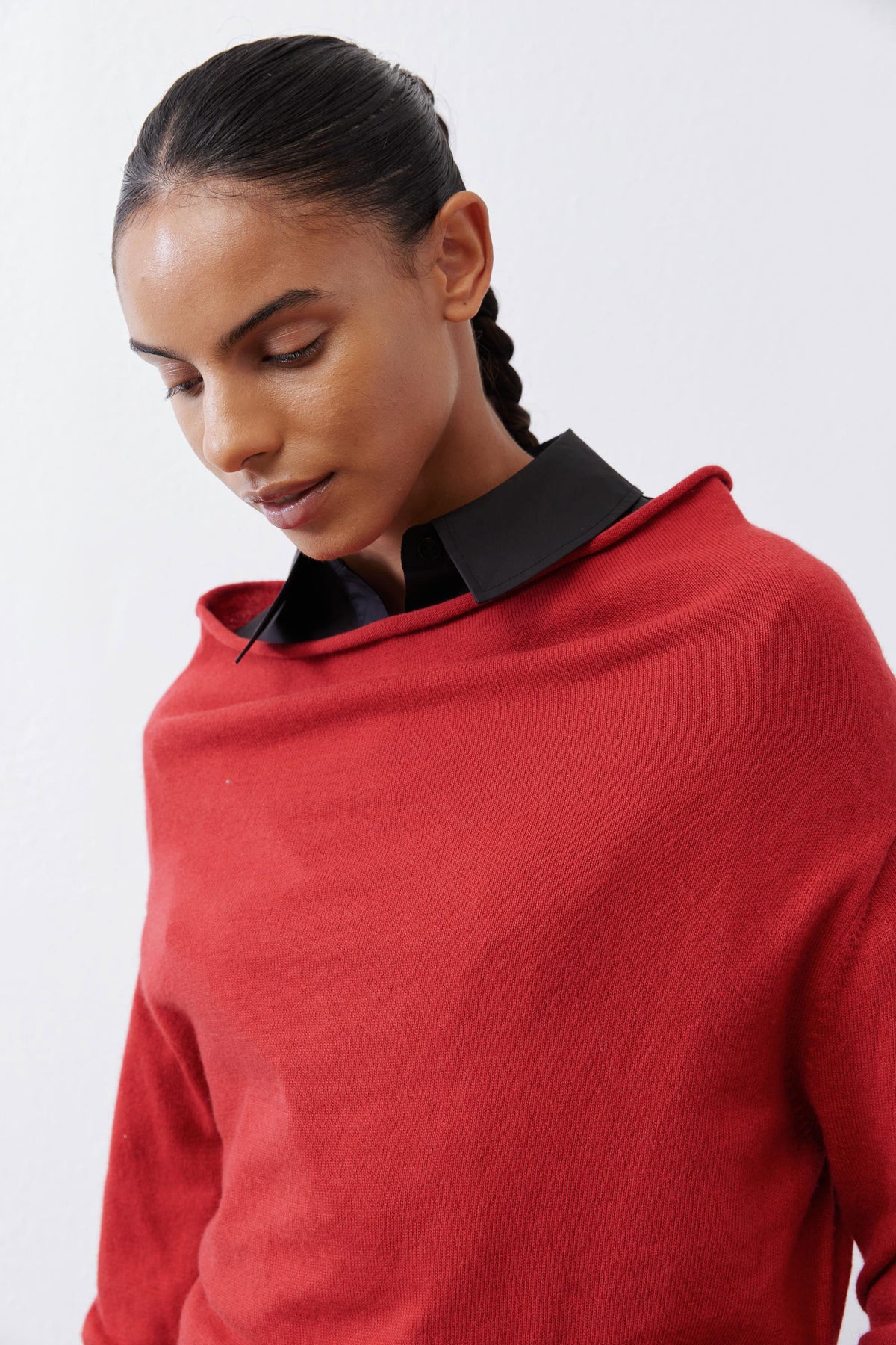 Red knit sweater close-up with black collared neckline and soft ribbing.
