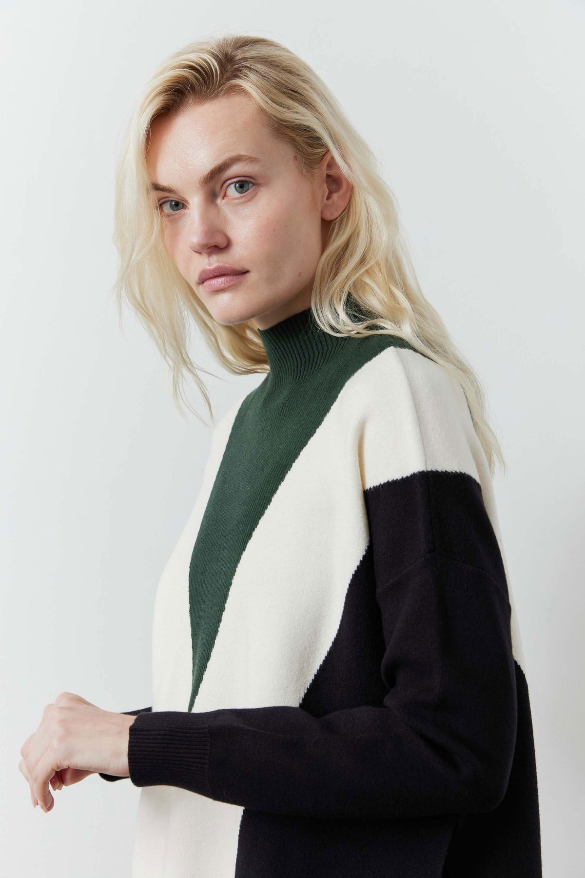 Chevron colorblock knit sweater with dark green neckline panel and cream/black sleeves
