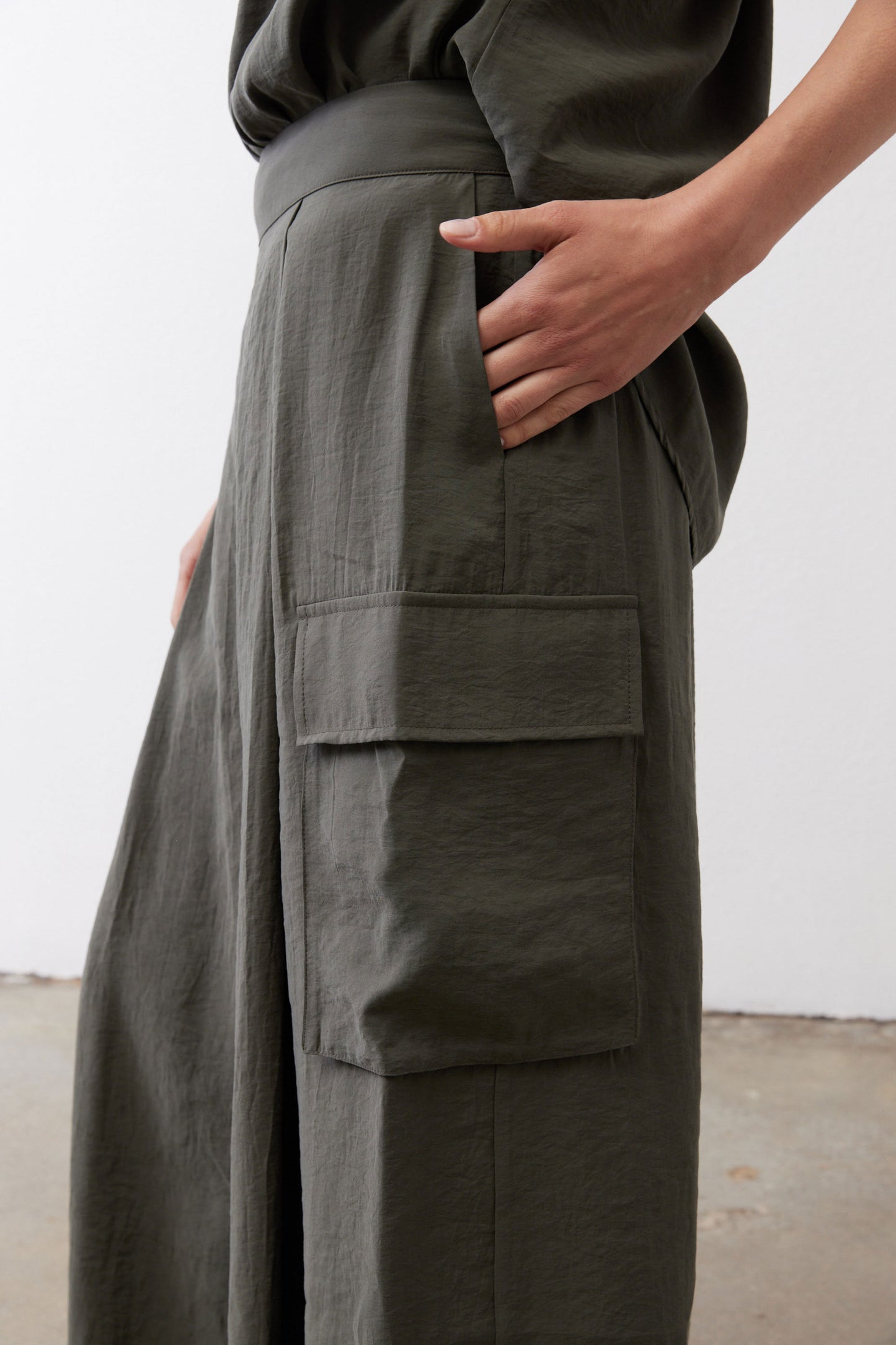 Olive cargo skirt pants with large front patch pockets and flap details