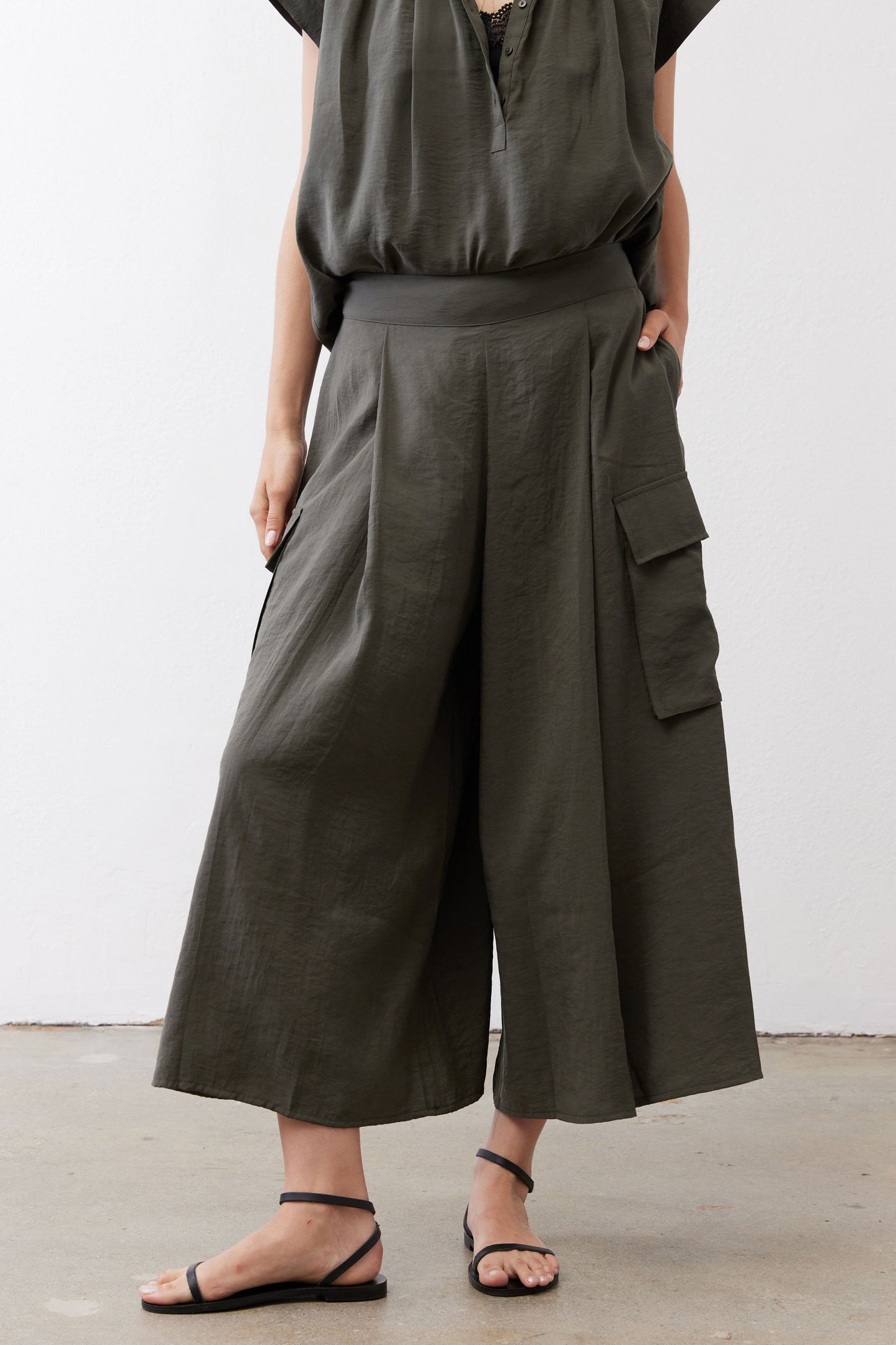 Olive cargo skirt pants with side cargo pockets and wide, draped legs