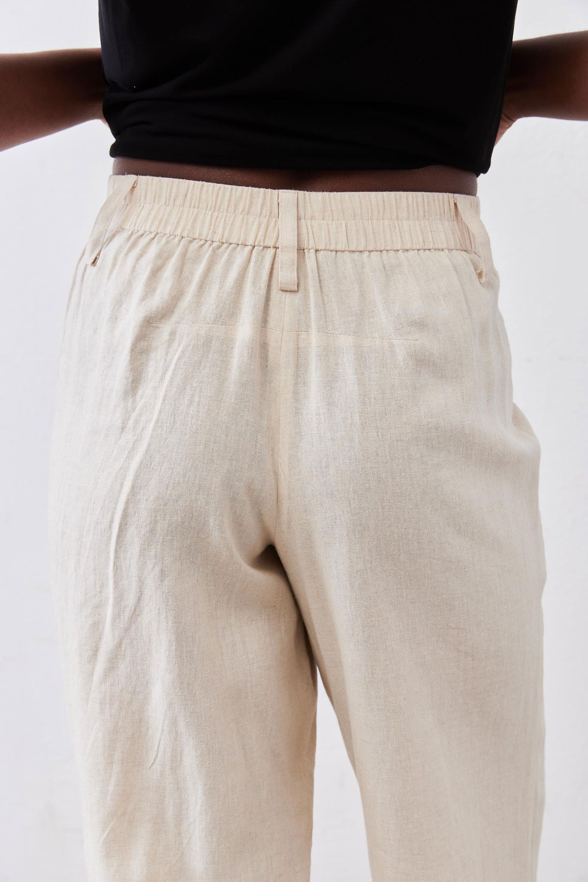 Close-up of oat linen A-line pants: elastic waistband and front seam detail.
