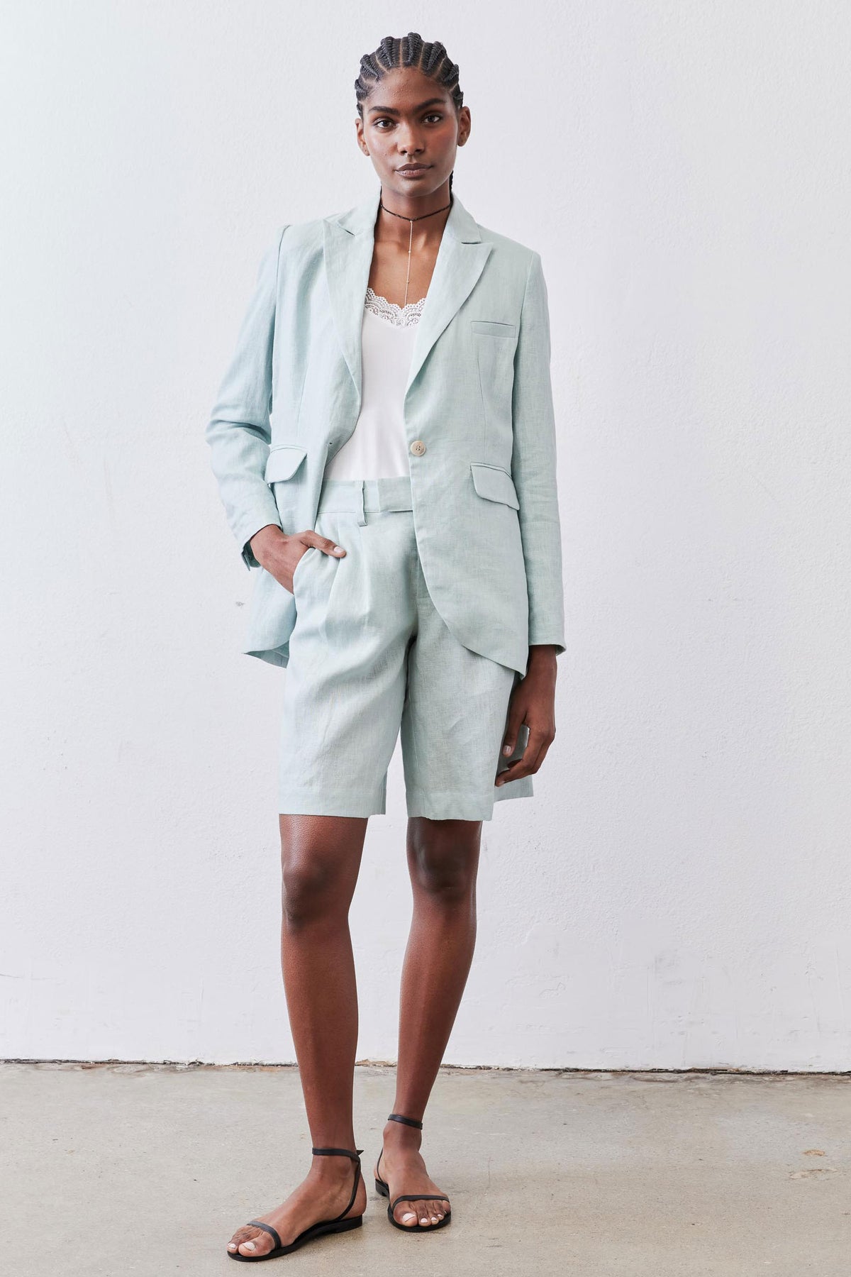 Mint pleated bermuda shorts on model, tailored front pleats and cuffed hem