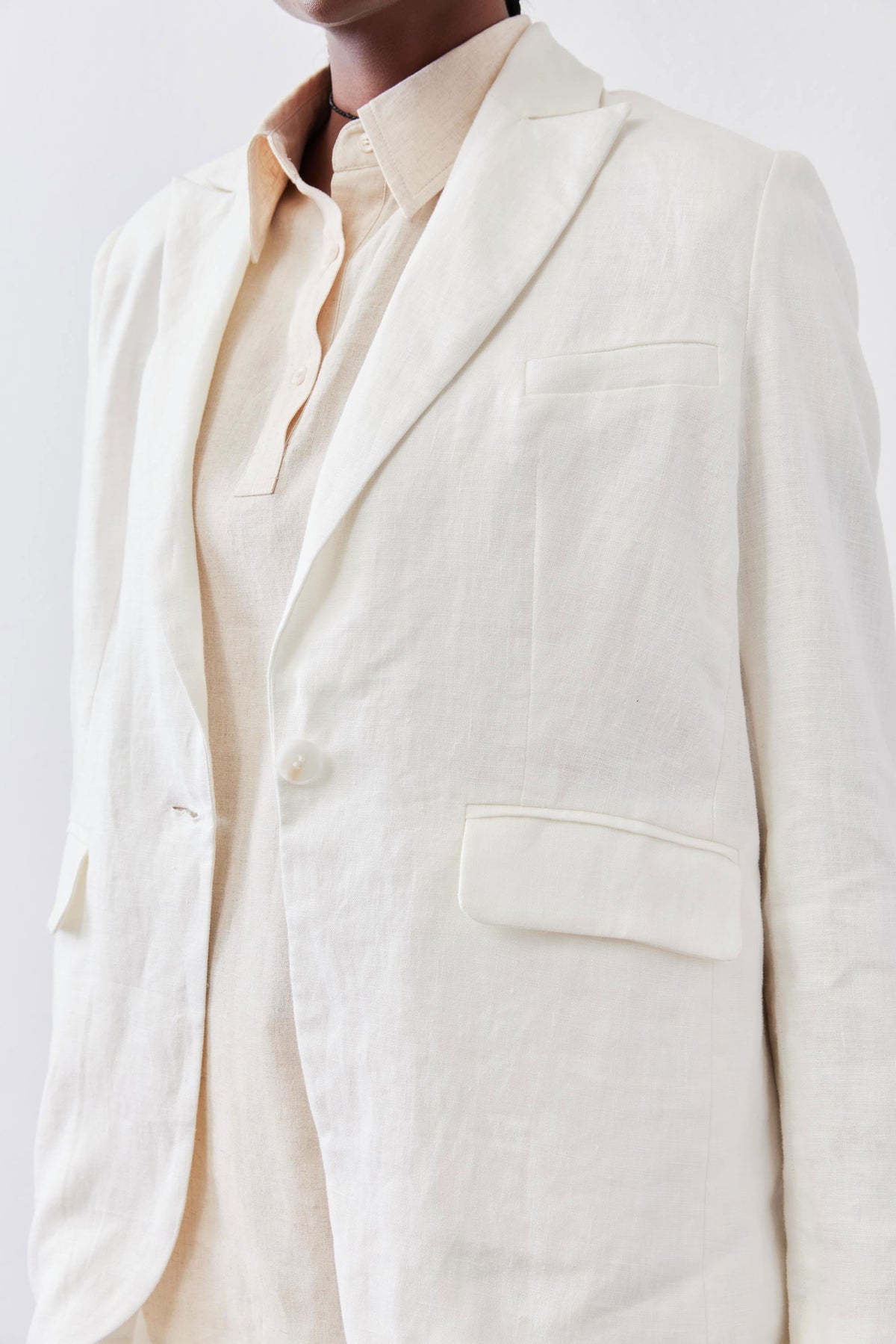 Vintage white linen blazer lapel and chest pocket detail over a light button-up
