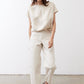 Off-white silk blouse with crew neck and short sleeves, worn untucked
