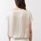 Off-white silk blouse back view with short sleeves, draped over light pants