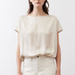 Off-white silk blouse with crew neck and short sleeves, loose drape over light pants