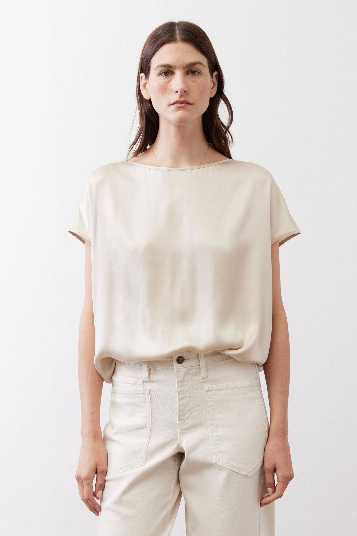 Off-white silk blouse with crew neck and short sleeves, loose drape over light pants