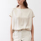 Off-white silk blouse front view with crew neck and short sleeves over light pants