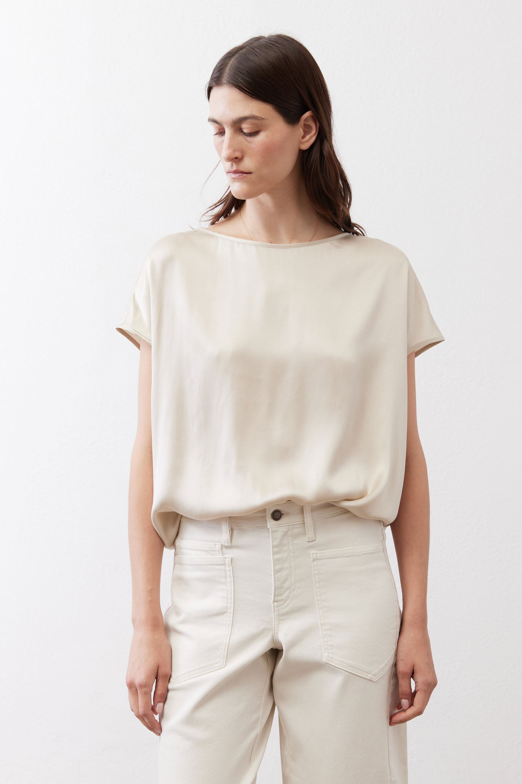 Off-white silk blouse front view with crew neck and short sleeves over light pants