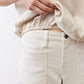 Off-white silk blouse sleeve and gathered hem detail over light pants