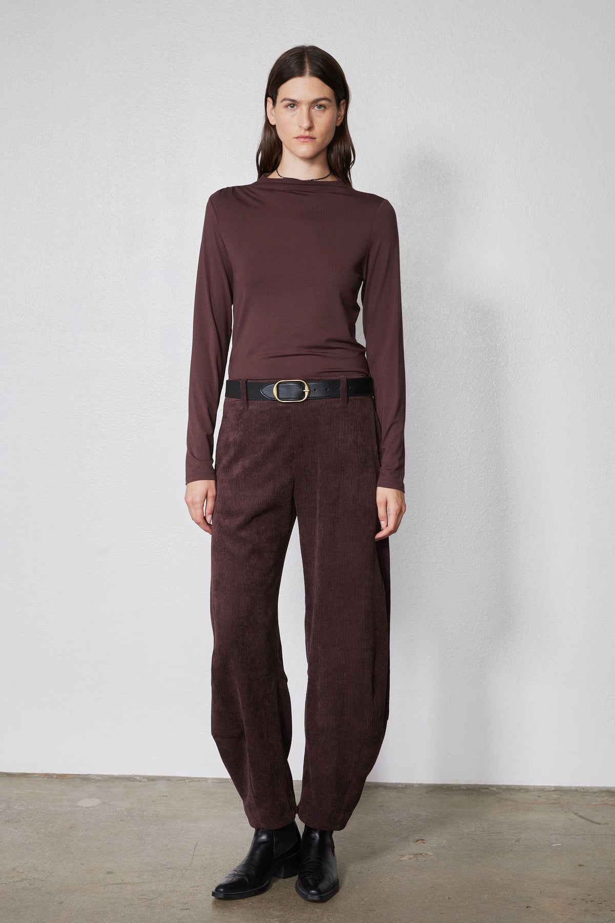 Brown long-sleeve mock-neck top with shoulder seam detailing and fitted silhouette