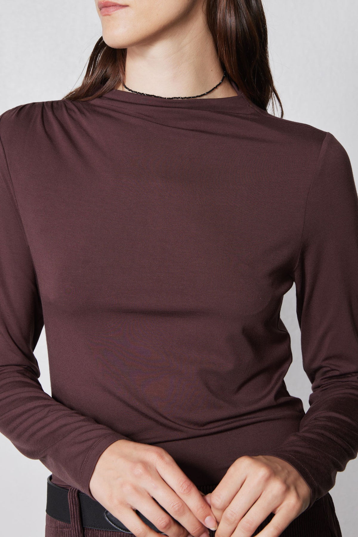 Brown mock-neck long-sleeve top with gathered shoulders and smooth fitted knit