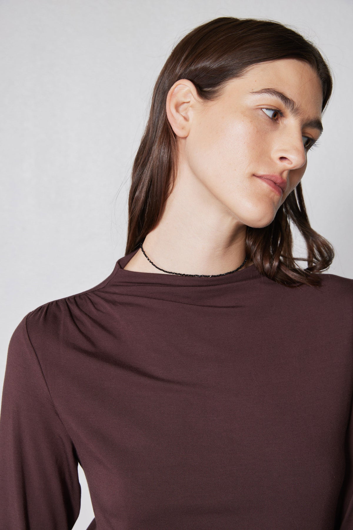 Brown mock-neck long-sleeve top with gathered shoulder line