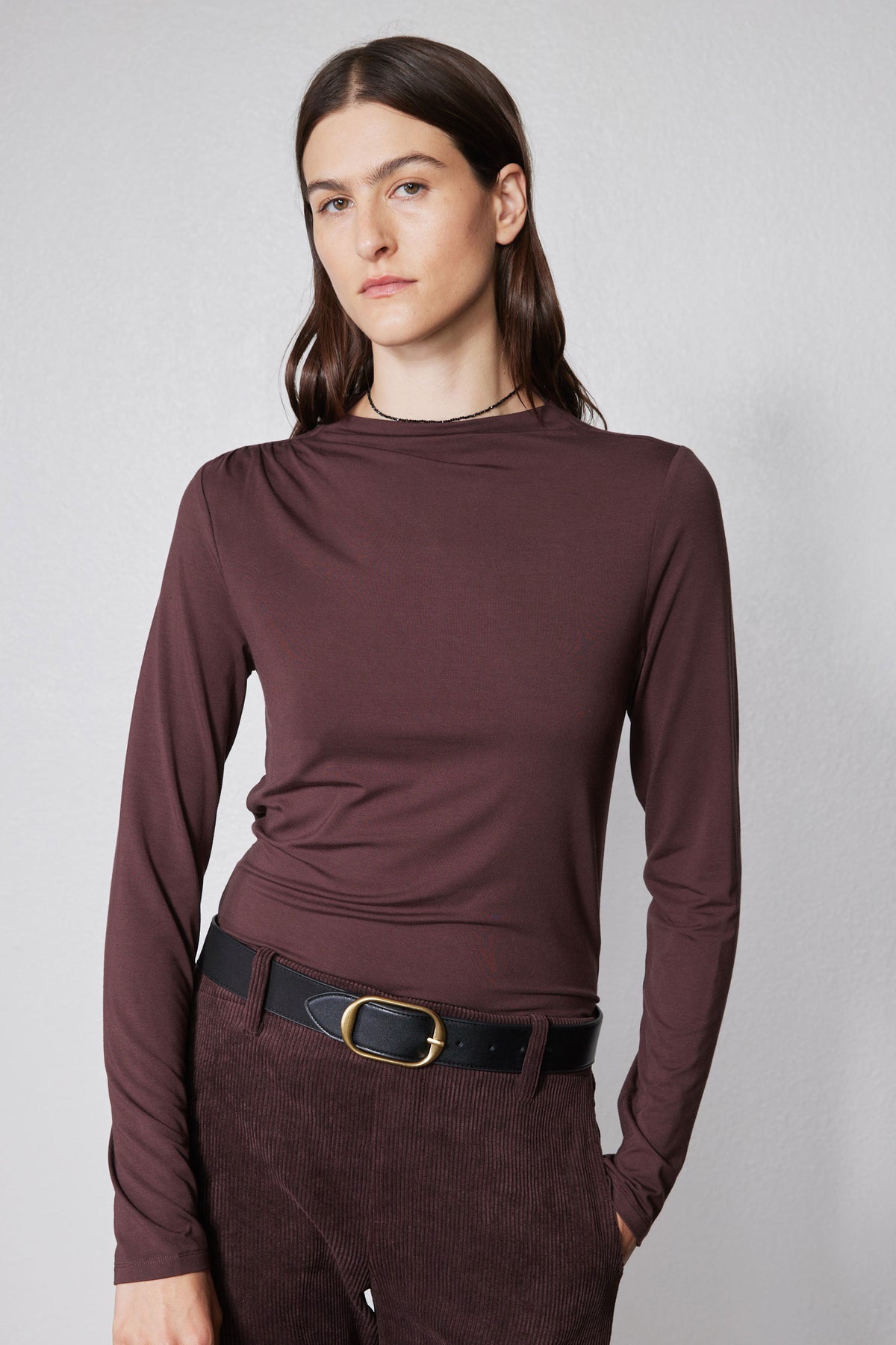Brown long-sleeve mock-neck top with shoulder seam detailing and fitted front