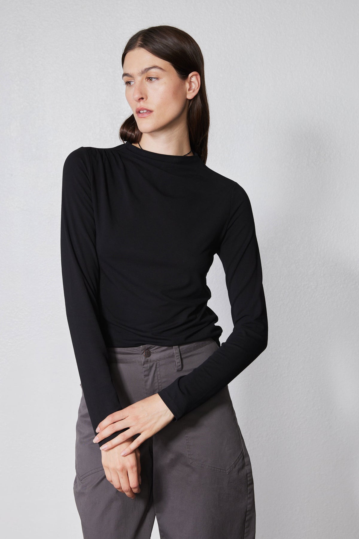 Black long-sleeve top with high neck and shoulder seam detail, side profile