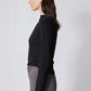 Black long-sleeve top with high neck and shoulder seam detail, side/back view