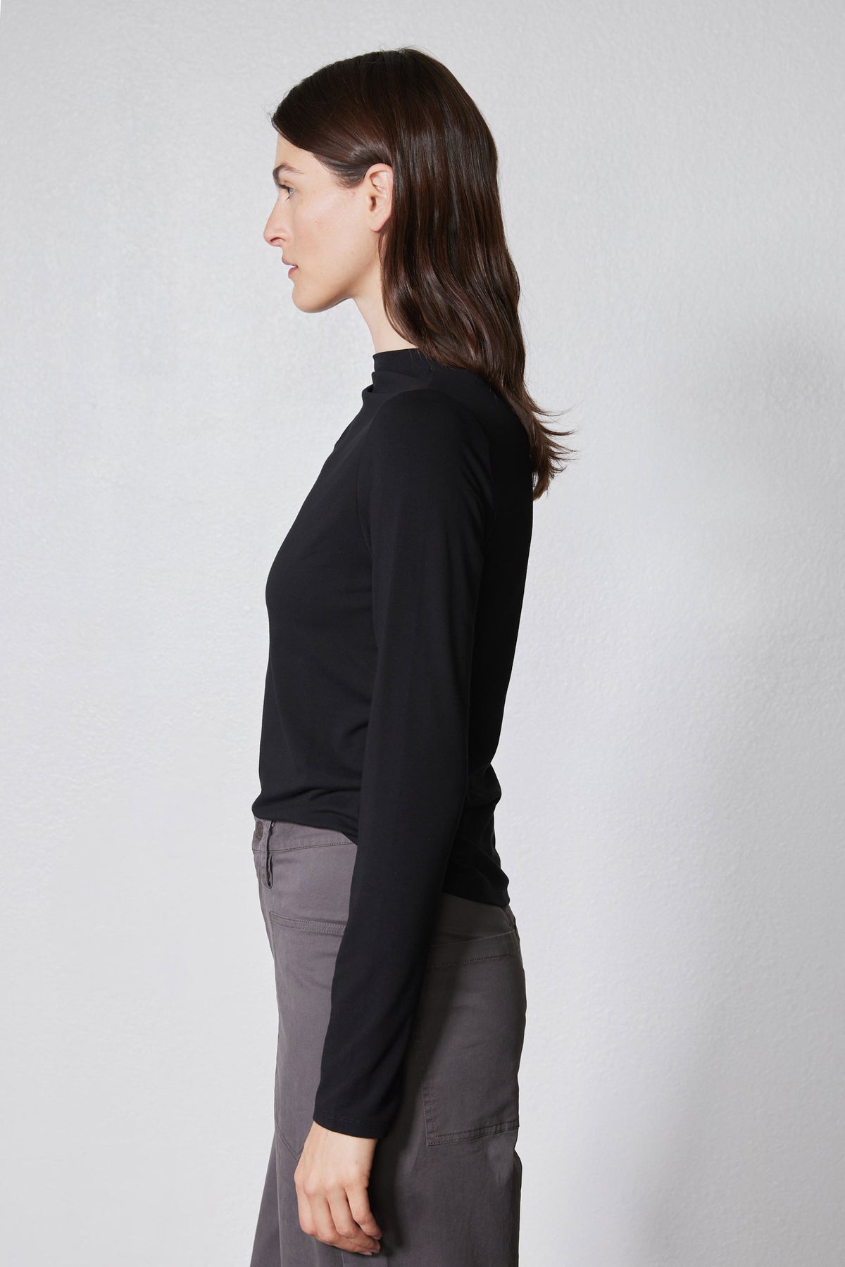 Black long-sleeve top with high neck and shoulder seam detail, side/back view