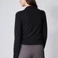 Black long-sleeve top with high neck and shoulder seam detail, back view
