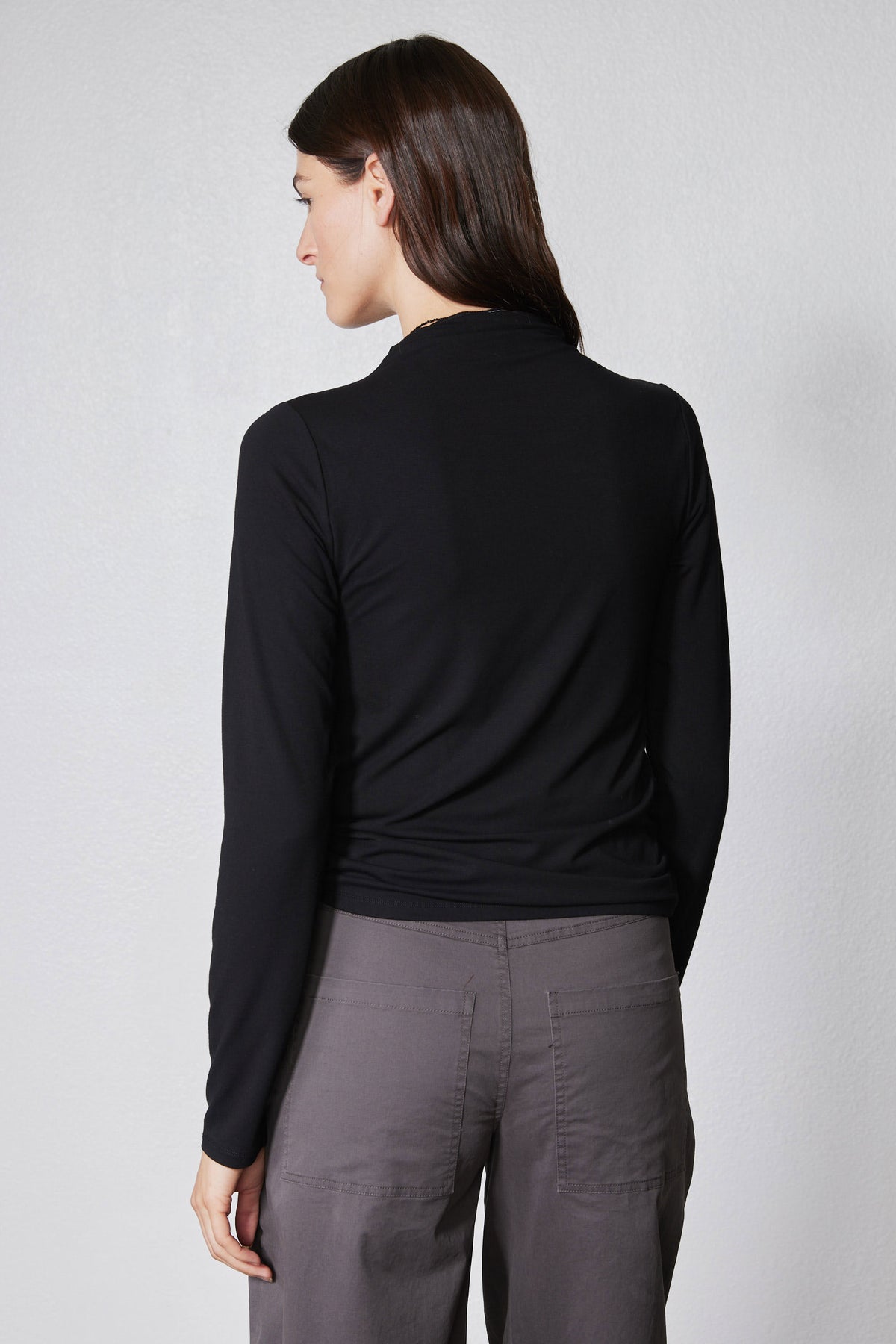 Black long-sleeve top with high neck and shoulder seam detail, back view