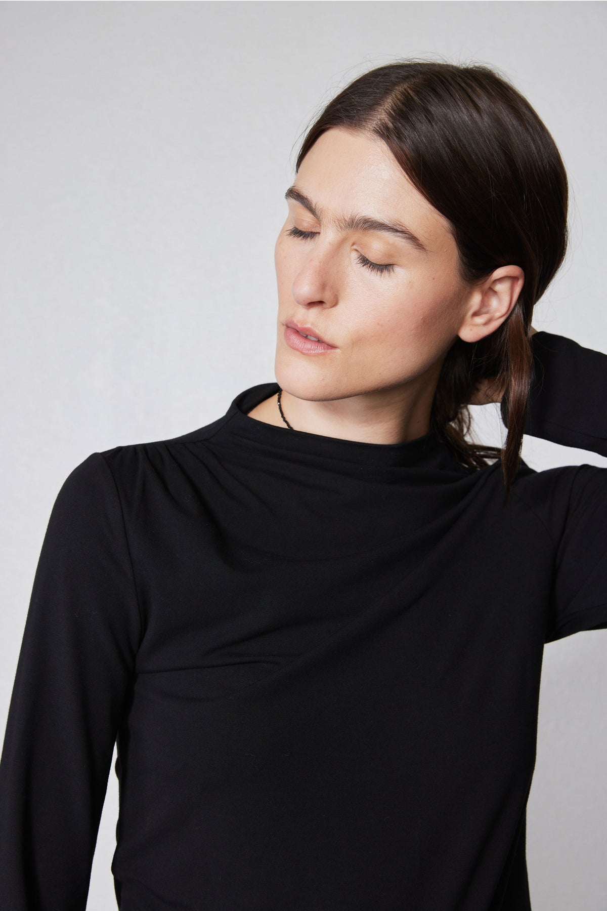 Black long-sleeve top close-up: high neck and shoulder seam detail