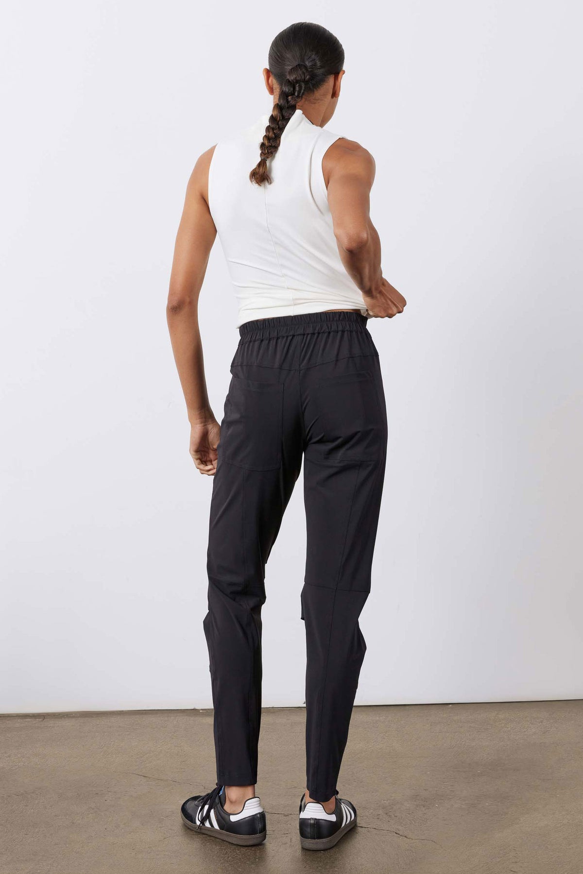 Black cargo jogger pants with elastic waist and cuffed legs, worn with sneakers