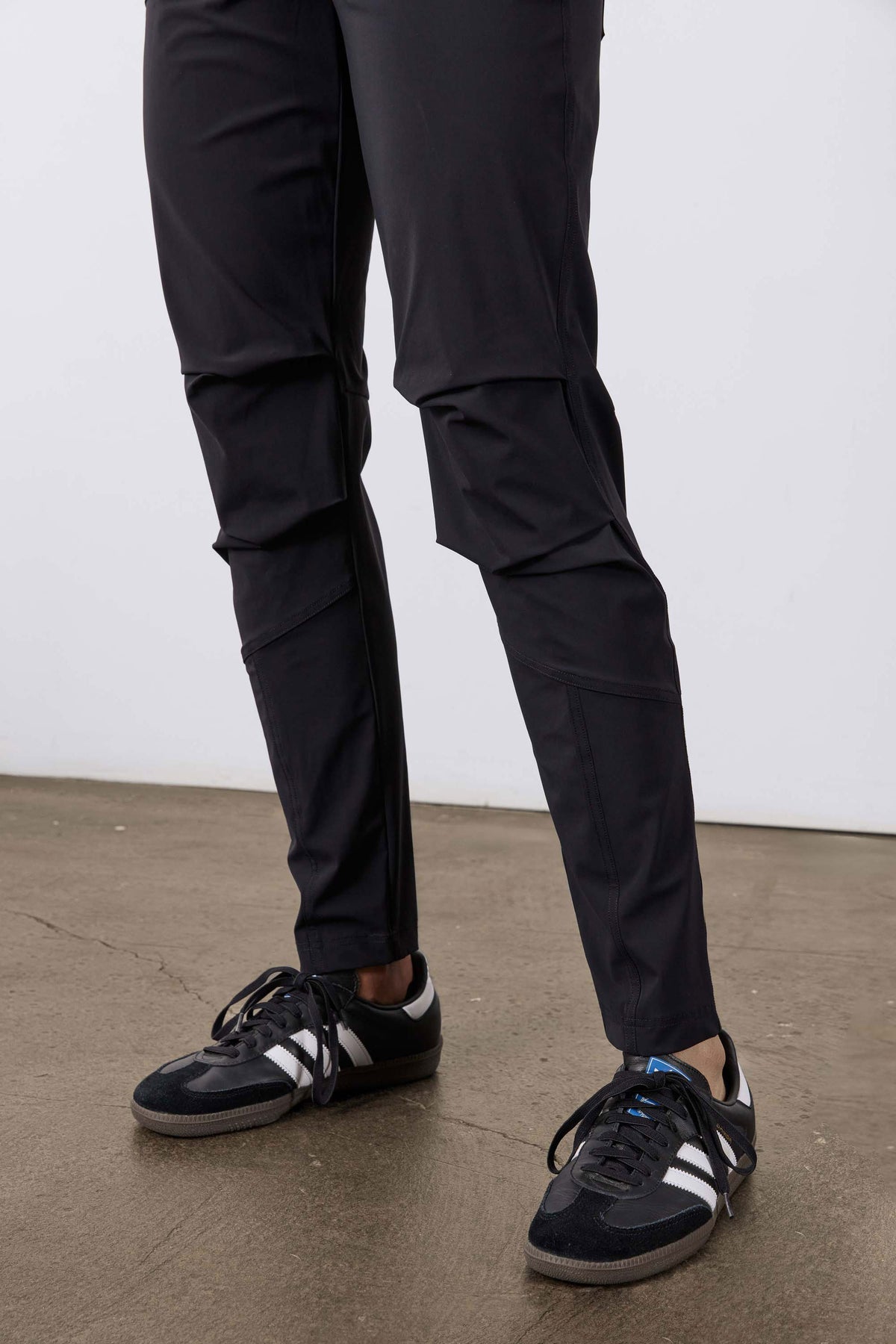 Black tapered jogger pants at ankle with side seam panels and sneakers