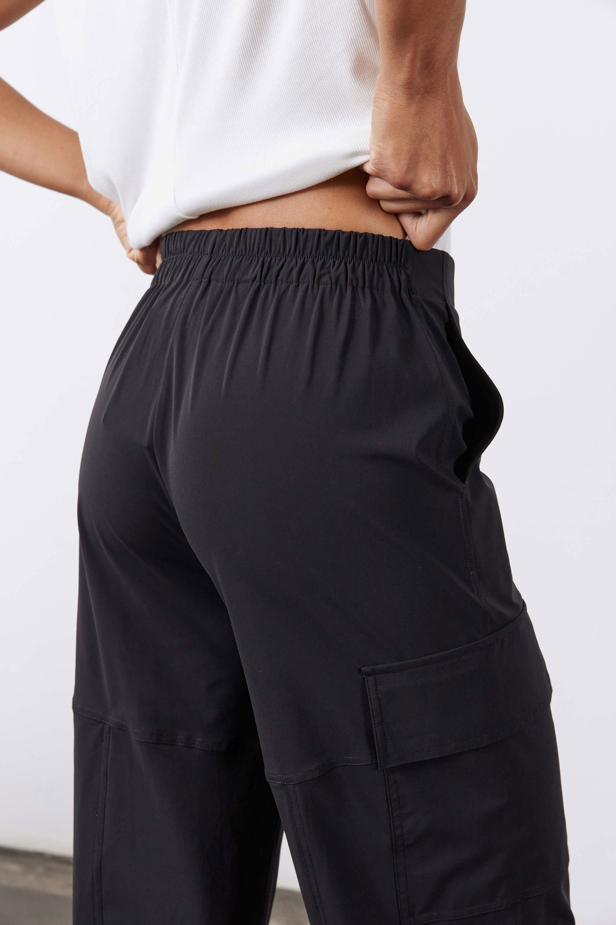 Black utility cargo pants close-up: elastic waistband and large side cargo pocket