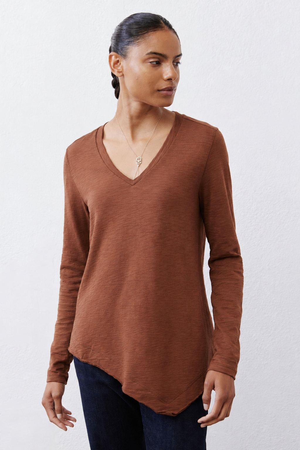 Rust-brown V-neck long-sleeve top with asymmetrical curved hem
